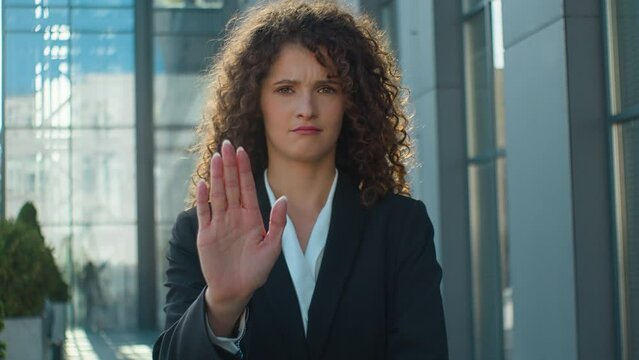 Serious Caucasian businesswoman girl stand crossed palms in city outdoors confident woman looking at camera hold hand in front stop gesture human rights protection protest not social discrimination 