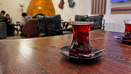 A glass of Turkish tea on a wooden table.