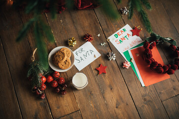 Christmas cookies and milk for Santa Claus on wooden floor under decorated Christmas tree.