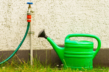 Watering green can on garden plot