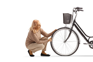 Woman kneeling and checking bicycle tire