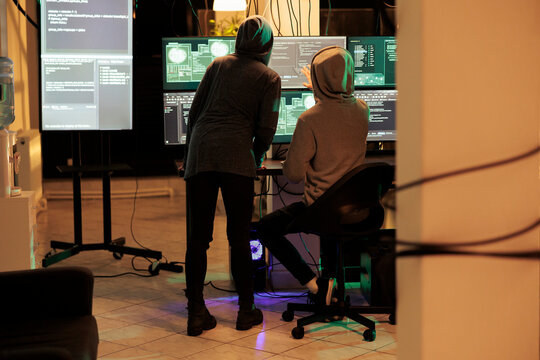 Team of cybercriminals cracking server encryption and hacking system, working on cyberterrorism at night. Young hackers doing criminal activity, stealing sensitive information. - Powered by Adobe