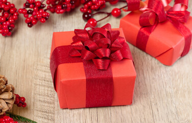 A box with a gift wrapped in red paper with a bow on the table