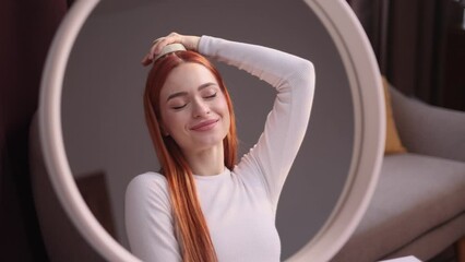 Portrait of pretty red haired woman looking at mirror reflection and doing self hair scalp massage with massager at home Concept of hair loss growth stimulation trichology self care