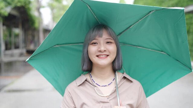 台北の華山1914文創園区の芸術的な建物で傘をさして色々な表情をしている若い台湾人女性 A young Taiwanese woman with an umbrella and various expressions on her face at an artistic building in the Huashan 1914 Cultural and Creative Park in Taipe