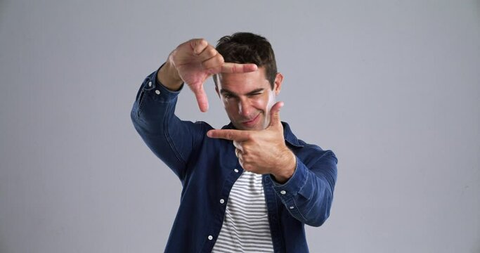 Man, face or finger frame in studio for review, profile picture or confident on gray background. Person, portrait and hands in planning ideas in photography, perspective and imagine border in mockup