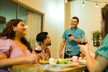 Excited dinner host making a toast drinking wine with friends