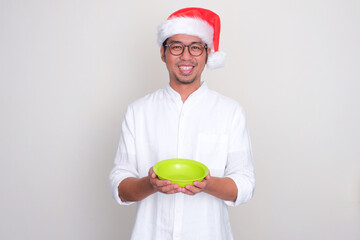 A man wearing christmas hat smiling happy while holding empty dinner plate