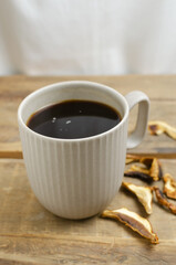 Mushroom coffee in a gray cup on a wooden background. The concept of a trendy beverage. The drink is good for health. Horizontal orientation. Selective focus.