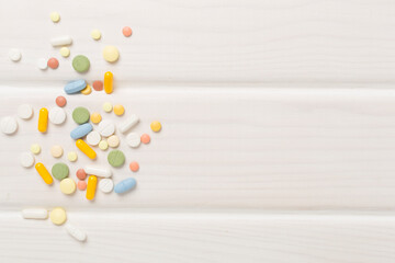 Different medical pills and capsules on wooden background, top view