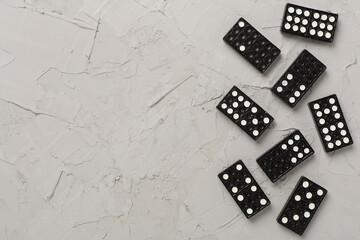 Black domino tiles on concrete background, top view