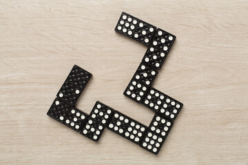 Black domino tiles on wooden background, top view