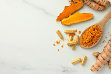 Aromatic turmeric powder, pills and raw roots on white marble table, flat lay. Space for text