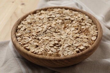 Wooden bowl with oatmeal on table, closeup