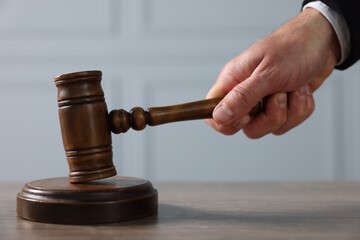 Judge with gavel at wooden table indoors, closeup