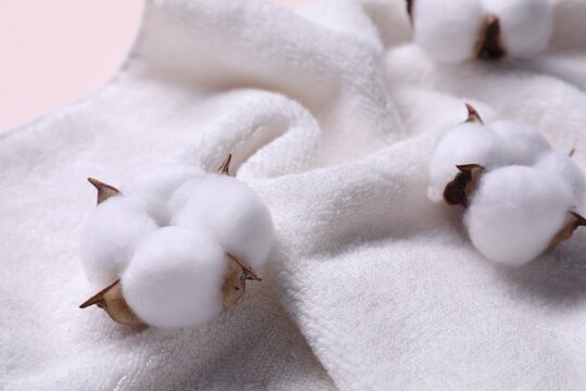 Fluffy cotton flowers on white terry towel, closeup