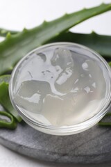 Aloe vera gel and slices of plant on white background, closeup