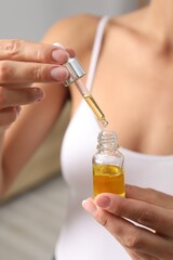 Fototapeta premium Woman with bottle of cosmetic serum on blurred background, closeup