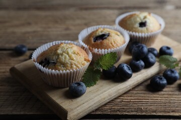 Delicious sweet muffins with blueberries and mint on wooden table, closeup