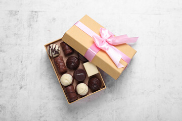 Open box with delicious chocolate candies on white table, top view