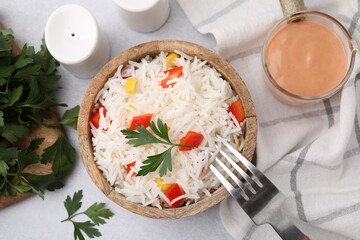 Bowl of delicious rice with vegetables and parsley served on table, flat lay