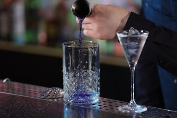 Bartender making fresh alcoholic cocktail at bar counter, closeup