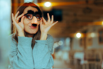 Funny Woman Wearing Silly Mustache Party Accessories Glasses . Girl with a sense of humor using disguise eyeglasses for a prank
 - obrazy, fototapety, plakaty