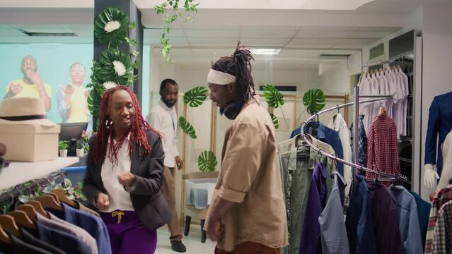 African american couple having fun in thrift shop, doing dance moves. Boyfriend and girlfriend enjoying themselves to nice SH clothing store music, dancing while shopping