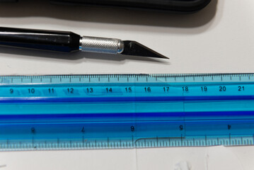 Precision Craftsmanship: Overhead View of a Hobby Knife and Blue Ruler on a Designer's Desk