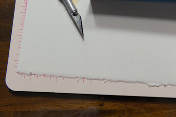 Artistic Precision: Close-Up of a Craft Knife and Ruler on Textured Watercolor Paper