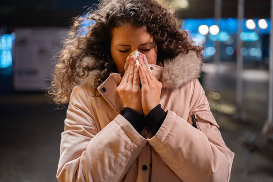 Young curly hair woman having flu, runny nose, using handkerchief closeup shot