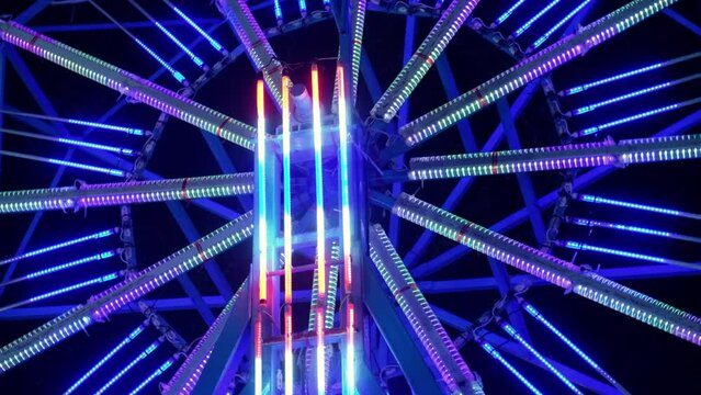 Funfair ferris wheel at night. Ferris wheel close up and light effect in motion at amusement park.