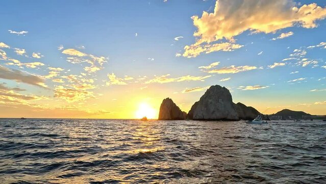 Boat in front of the sun at a sunset in Cabo San Lucas Mexico, 4k