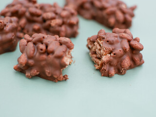 mini chocolate bar with peanut, caramel and puffed rice isolated on green.