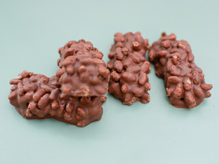 mini chocolate bar with peanut, caramel and puffed rice isolated on green.