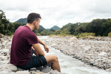 thoughtful man sitting on the bank of a river