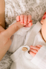 A newborn baby is holding their mother's finger 