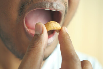 closeup of male mouth eating a cashew nut 
