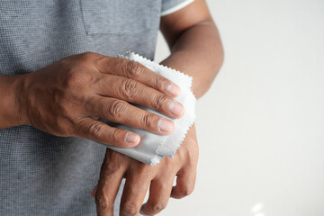  man disinfecting his hands with a wet wipe.