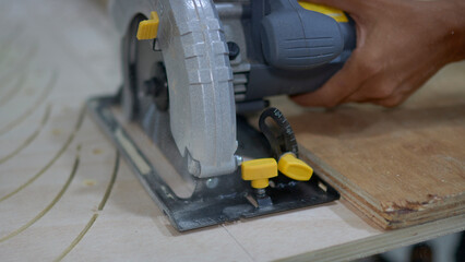 the master works with a manual circular saw on wood, close-up
