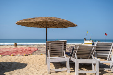 wooden beach umbrellas and sunbeds loungers on sandy beach of ocean