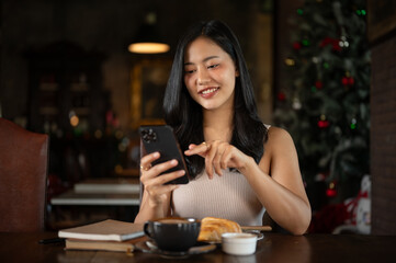 Attractive Asian woman using smartphone in her luxury living room.