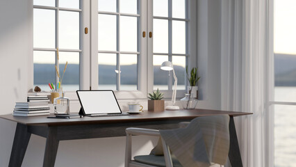 Minimal cozy home office space with blank screen mock up tablet on dark wooden table, large window with sea view.