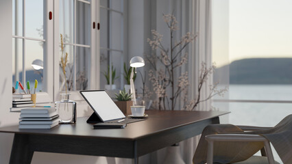 Minimal cozy home office space with blank screen mock up tablet on dark wooden table, large window with sea view.
