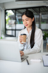 Young beautiful Asian businesswoman having a coffee break after a meeting