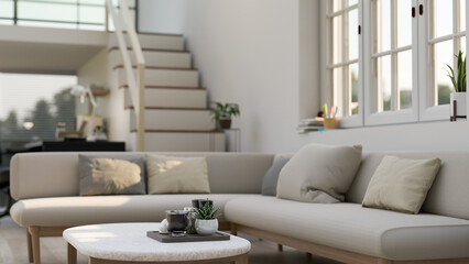 A coffee table in a modern and comfortable living room with a corner couch against the window.