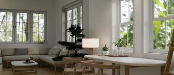 A minimal dining table against the window in a beautiful cosy Scandinavian living room.