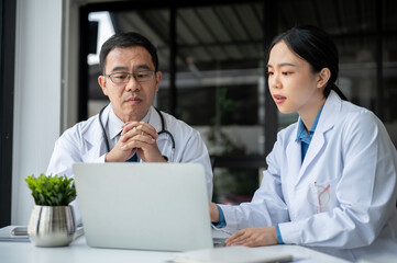 Obraz premium Young female doctor is asking for advice from a professional senior male doctor in the office room.