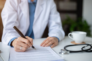 Close-up image of an experienced female doctor writing a medicine prescription for a patient.