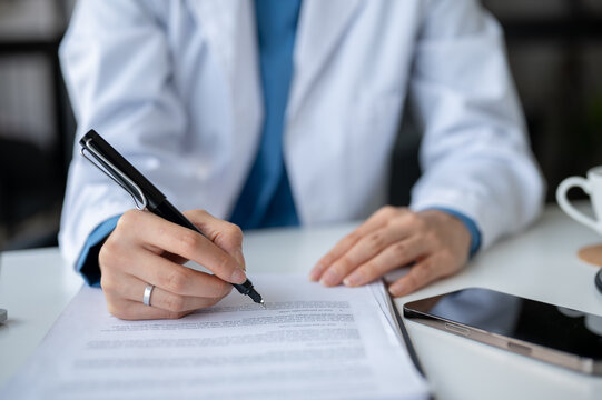 Close-up image of a professional female doctor writing a medicine prescription for a patient.